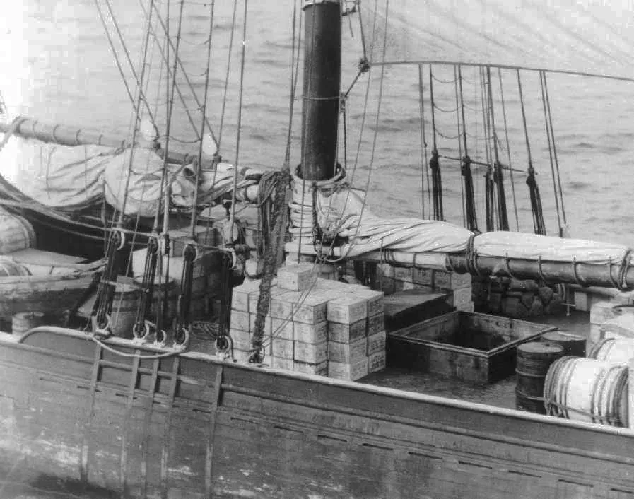 Cases of liquor stacked on the deck of a sailing ship