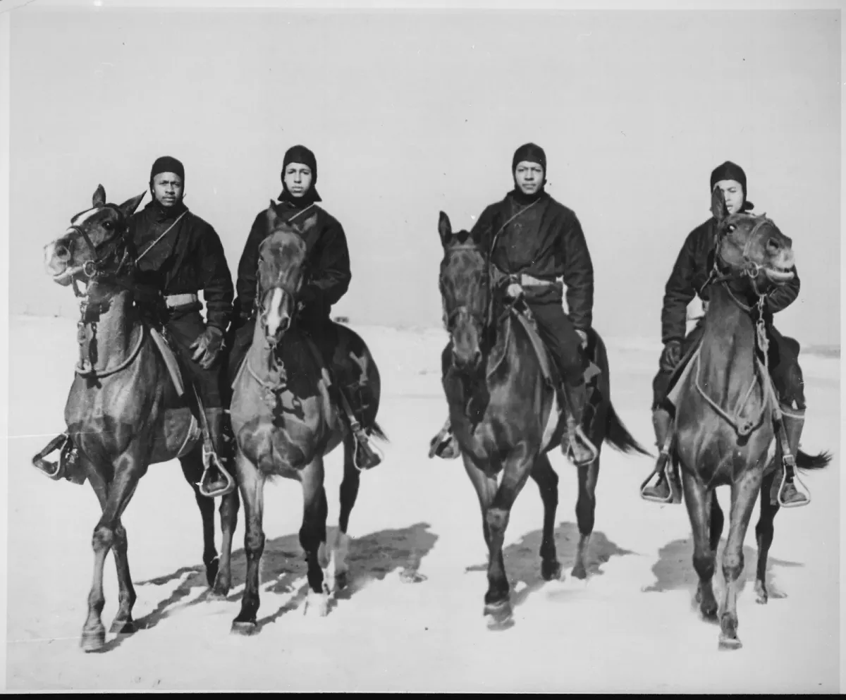 Four Coast Guardsmen on horseback on a beach