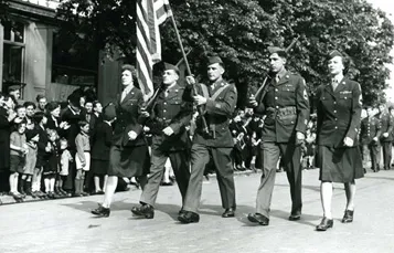 French civilians in Reims, France, the site of the German surrender, applaud American soldiers and WACs on parade during V-E Day celebration.